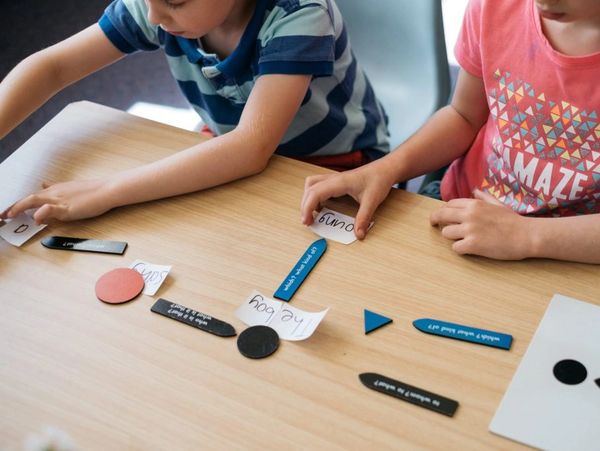 Children playing a language learning game with word cards and shapes.