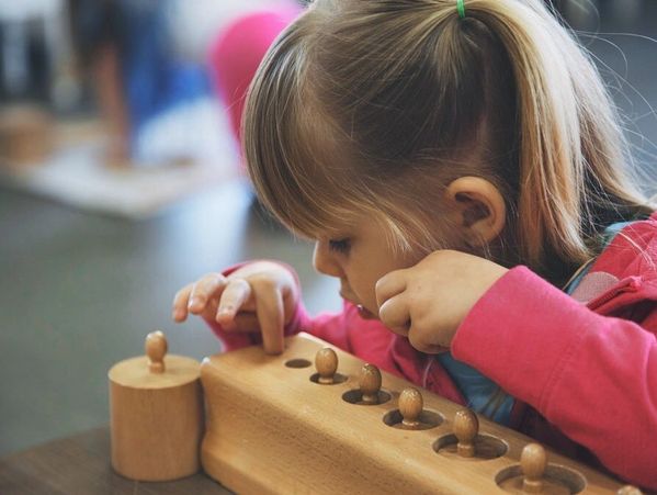 Young girl playing with a wooden peg board.
