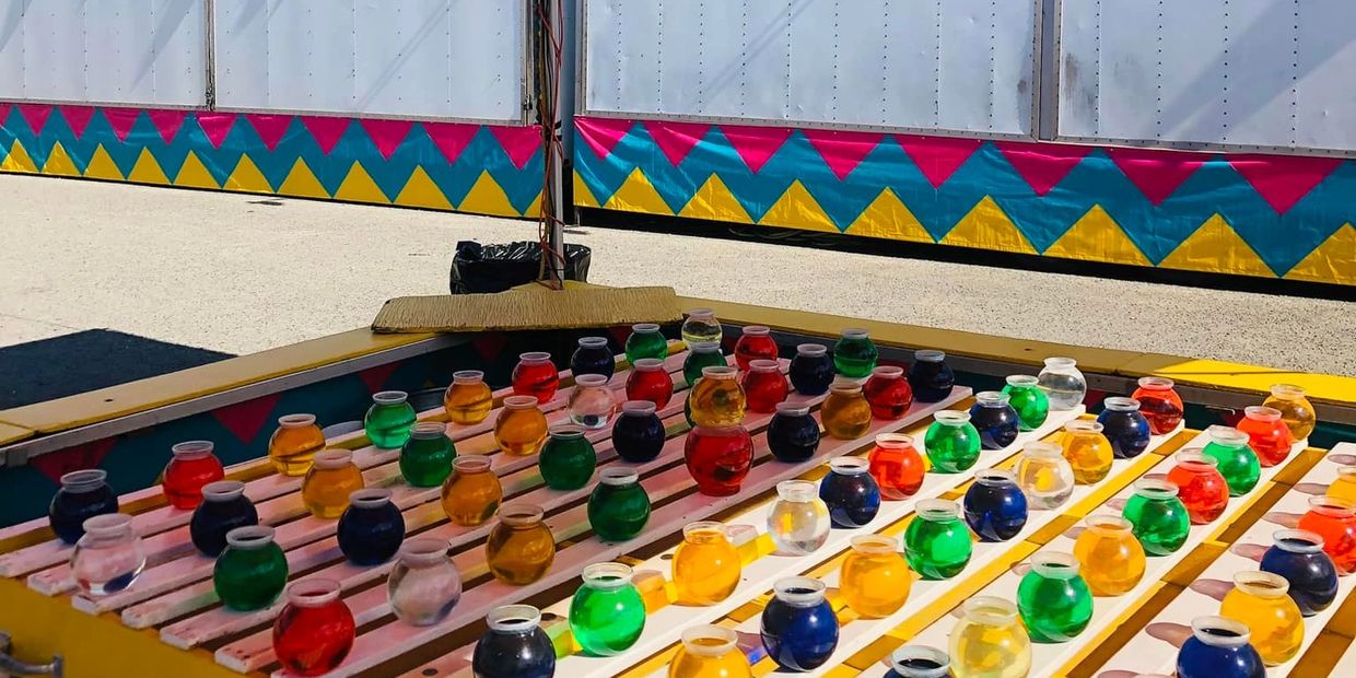 Colorful goldfish bowls arranged at a carnival game booth.