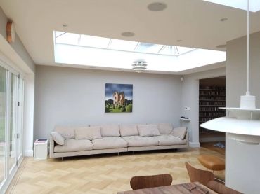Modern living room with a large beige sofa under a skylight.