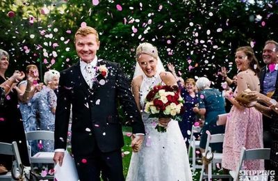 Just married couple walking down the aisle with confetti in the air.