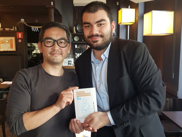 Two men holding a book together and smiling in a cozy indoor setting.