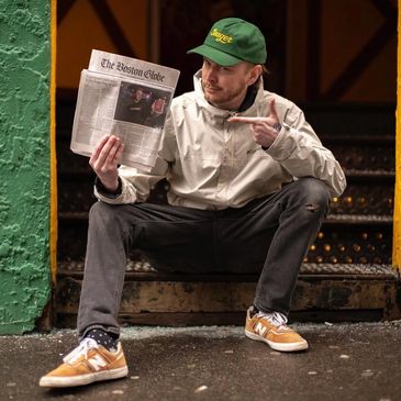 Man sitting on steps holding up a newspaper.
