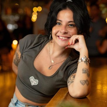 Smiling woman with tattoos at a bar.