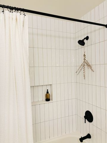 Bathroom with vertical stacked white subway tile and black hardware.