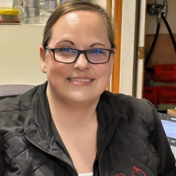 Smiling woman wearing glasses and a black jacket.