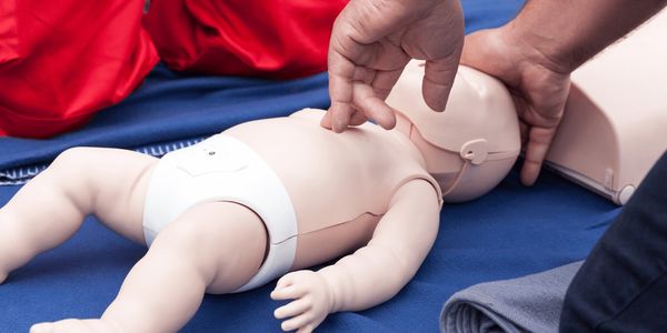 Person practicing CPR on a baby mannequin.