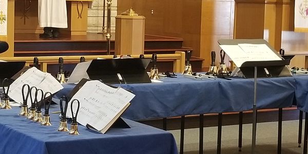Handbells and sheet music set up on tables in a church.