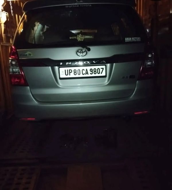 Rear view of a silver Toyota Innova with a visible license plate in dim lighting.