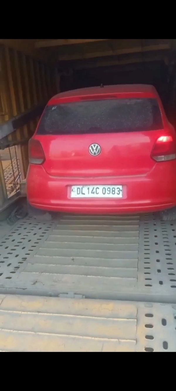 Red Volkswagen car inside a shipping container with license plate DL14C 0983.