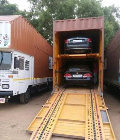 Two black cars loaded inside a yellow car carrier truck.