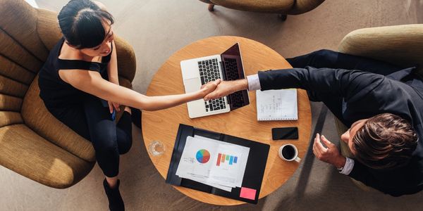 Two professionals shaking hands over a business table.