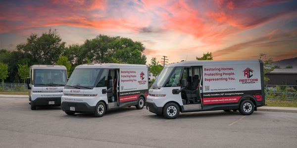 Three Restore Canada vans parked at sunset.