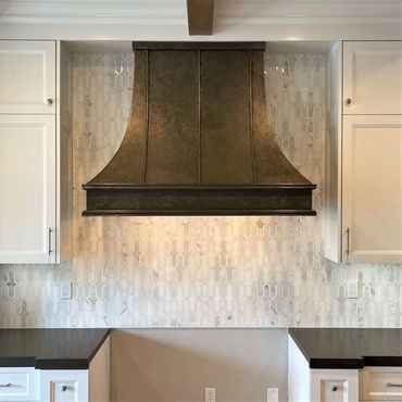 Custom steel kitchen hood with patina finish. Sweeping body style with half round 