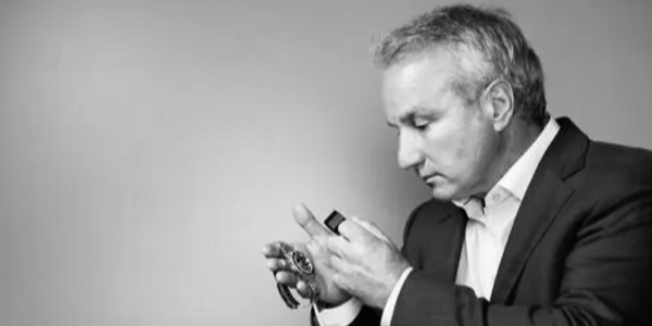 Man in suit carefully examining a watch.