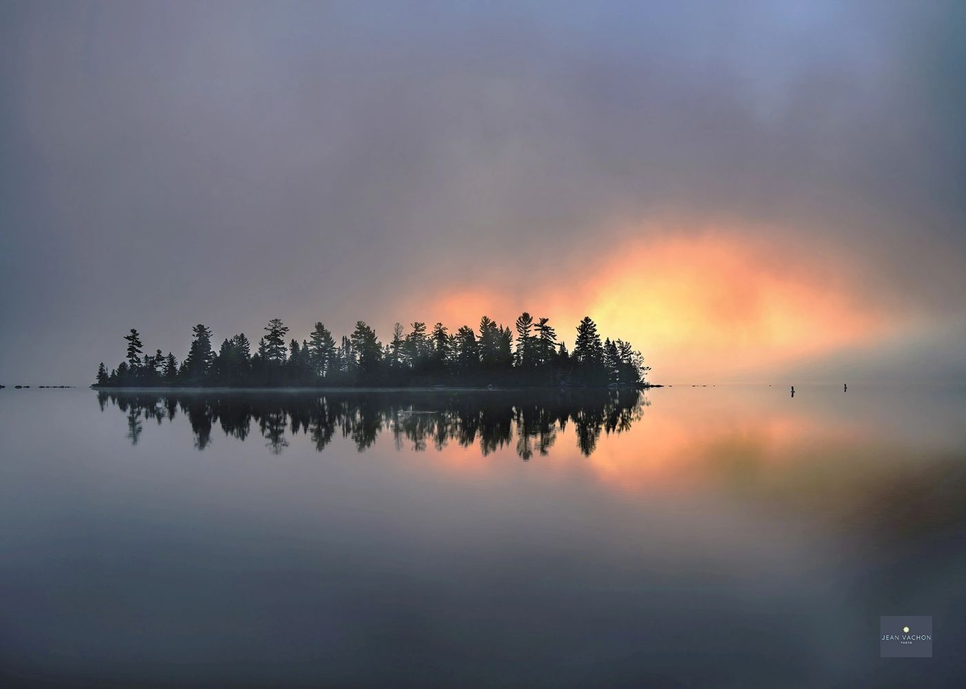 Fine art photography of a foggy sunrise behind an island, on a calm lake