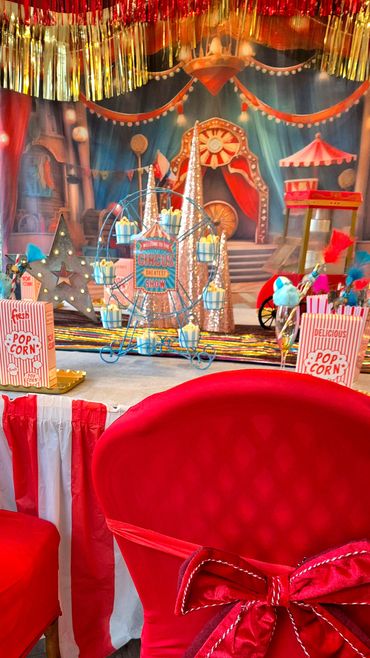 The set up of a circus party with table decor, backdrop and chair covers