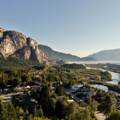 A scenic town nestled between mountains and a winding river under a clear sky.