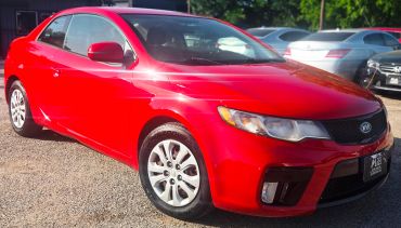 Bright red Kia sedan in a parking lot.