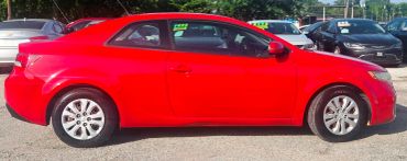 Bright red two-door coupe parked under sunlight.