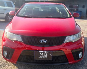 Front view of a red Kia car with a dealer plate.