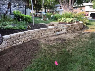 A neatly built stone retaining wall with a small stairway in a garden.