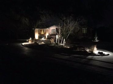 A house illuminated by outdoor lights at night.