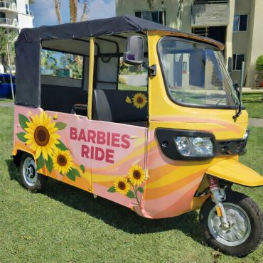 Colorful tuk-tuk with 'Barbies Ride' and sunflower decorations.