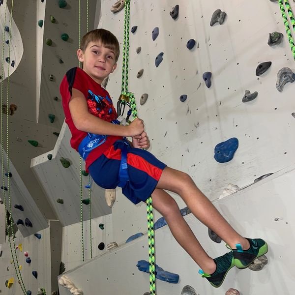 Young boy rappelling in a rock climbing gym