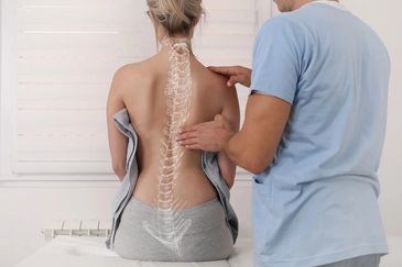 Doctor examining a patient's lower back, symbolizing pain management or chiropractic care.