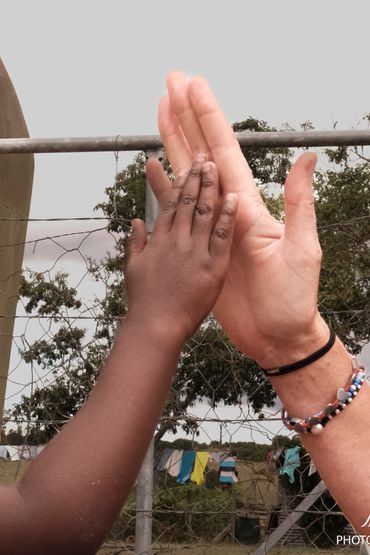 Un high five haut en couleurs avec la main d'une enfant noire et la main d'une adulte blanche