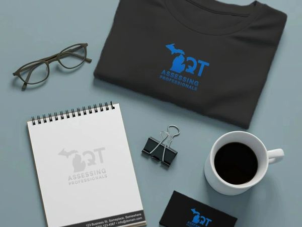 Workspace with branded items including T-shirt, notebook, business card, glasses, and coffee.