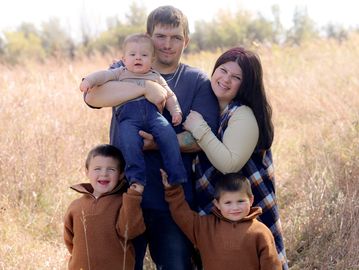 Family of five posing outdoors in a field.