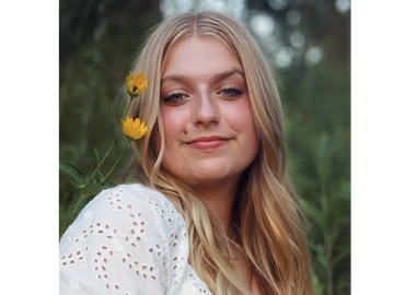 Smiling young woman outdoors with yellow flowers.