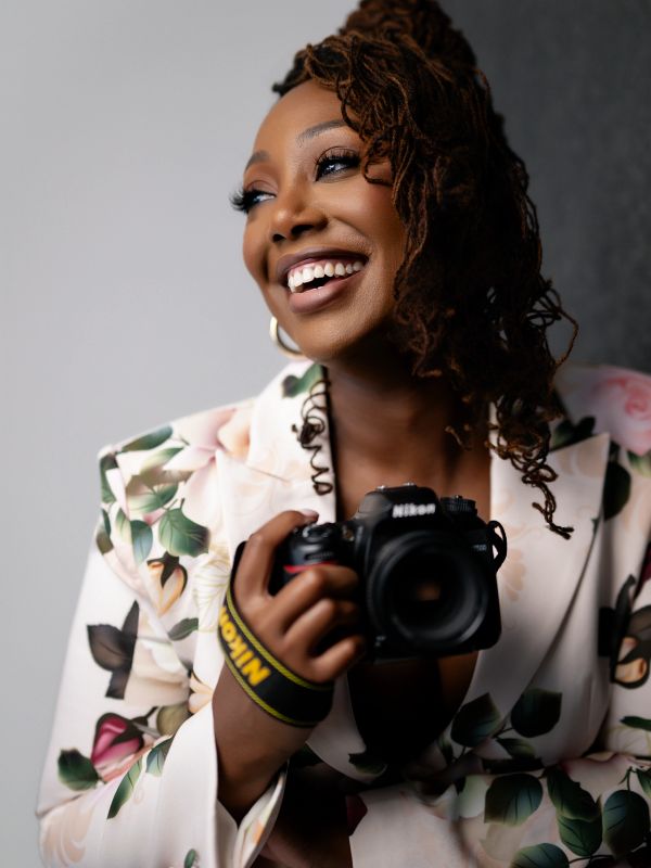 Smiling woman holding a Nikon camera.