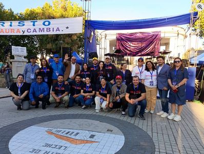 Group of people posing in front of a banner at an outdoor event.