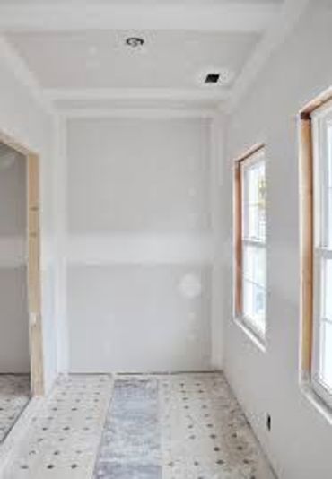 A small, unfinished room under construction with drywall and windows.