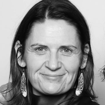 Black and white portrait of a smiling woman with detailed earrings.