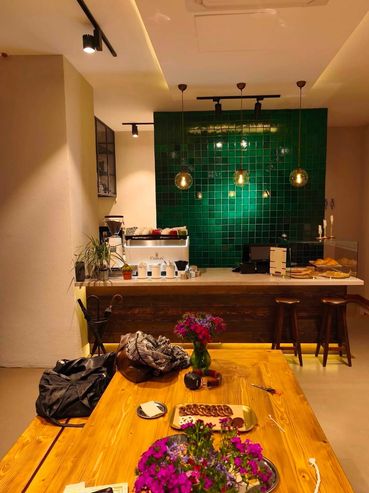 Cozy coffee bar with green tiled wall and wooden furniture.