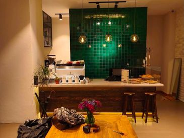 Cozy coffee bar with green tiled wall and wooden furniture.