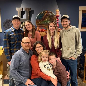 A family gathering with multiple generations smiling indoors.