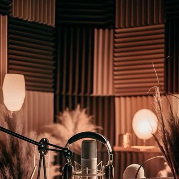 A cozy podcast or recording setup with microphone, headphones, and laptop.