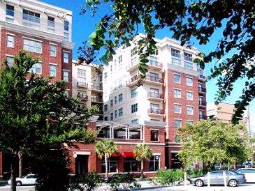 Modern residential buildings with trees and parked cars.