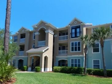 Three-story apartment building with palm trees.