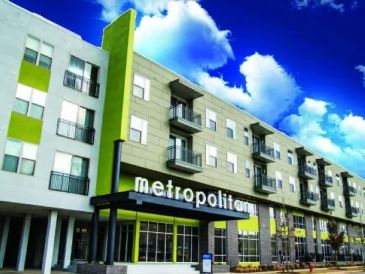 Modern apartment building named "metropolitan" under a bright blue sky.