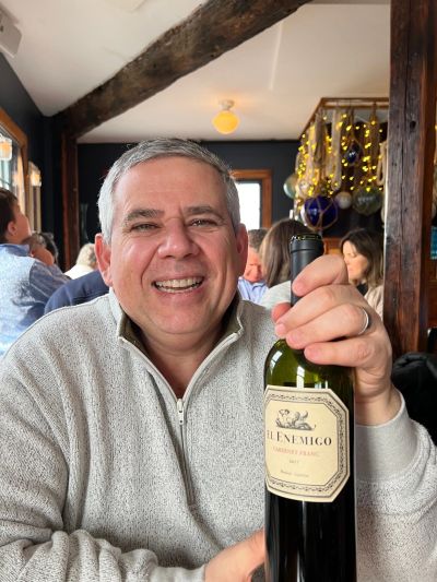 Smiling man holding a bottle of El Enemigo Cabernet Franc wine.