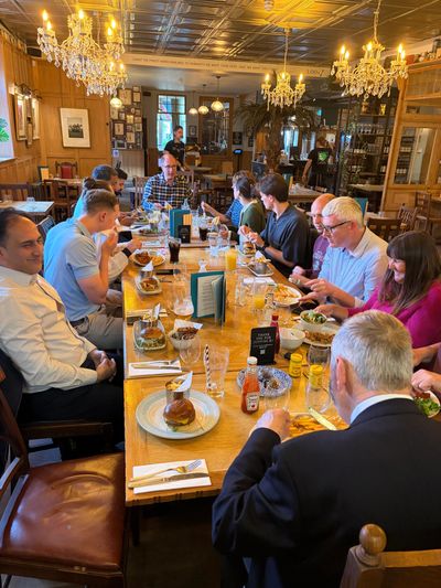 Group enjoying a meal together in a cozy restaurant with chandeliers.