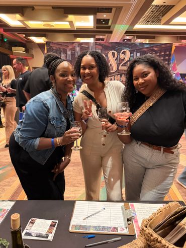 Three women enjoying a wine tasting event, smiling and holding glasses of wine.