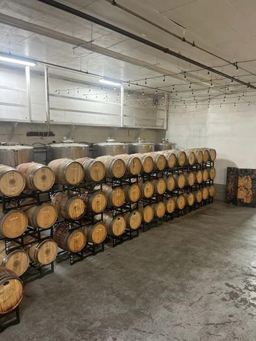 Rows of wooden barrels stored on racks inside a winery cellar.