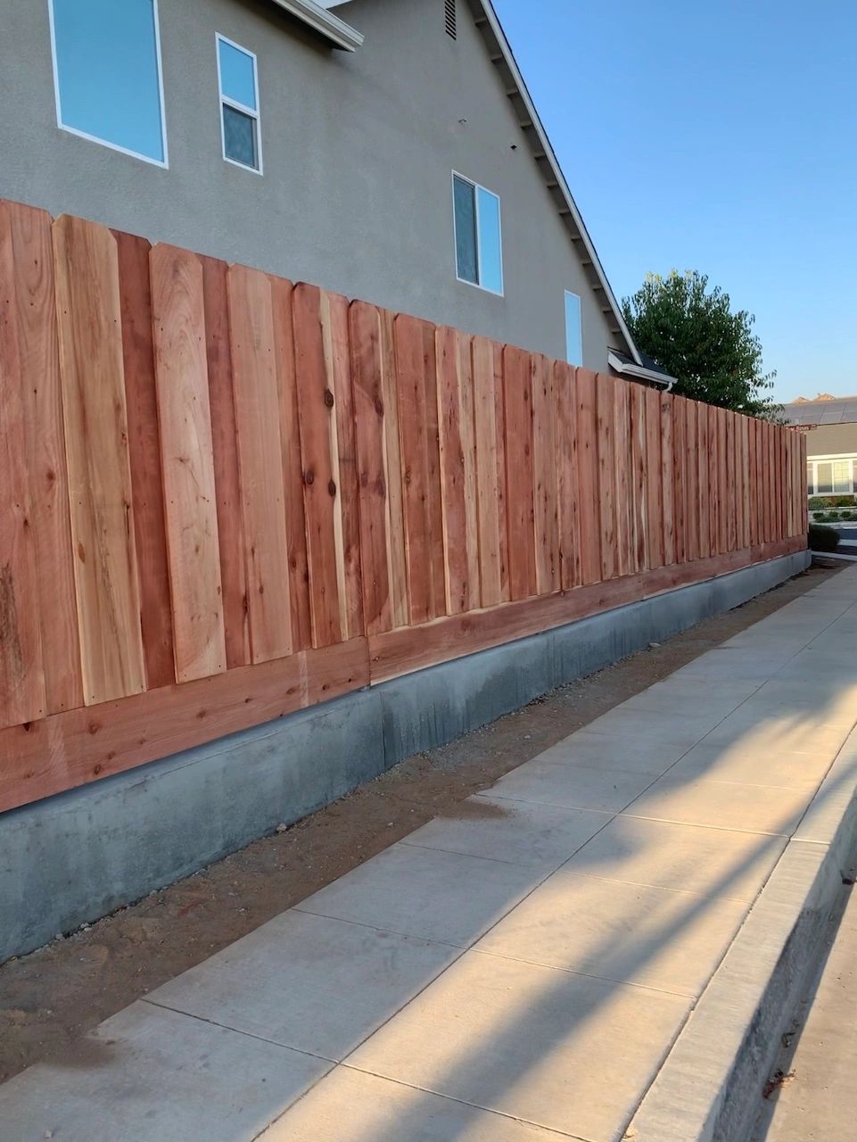 Side wooden fence with grass boards and concrete border
